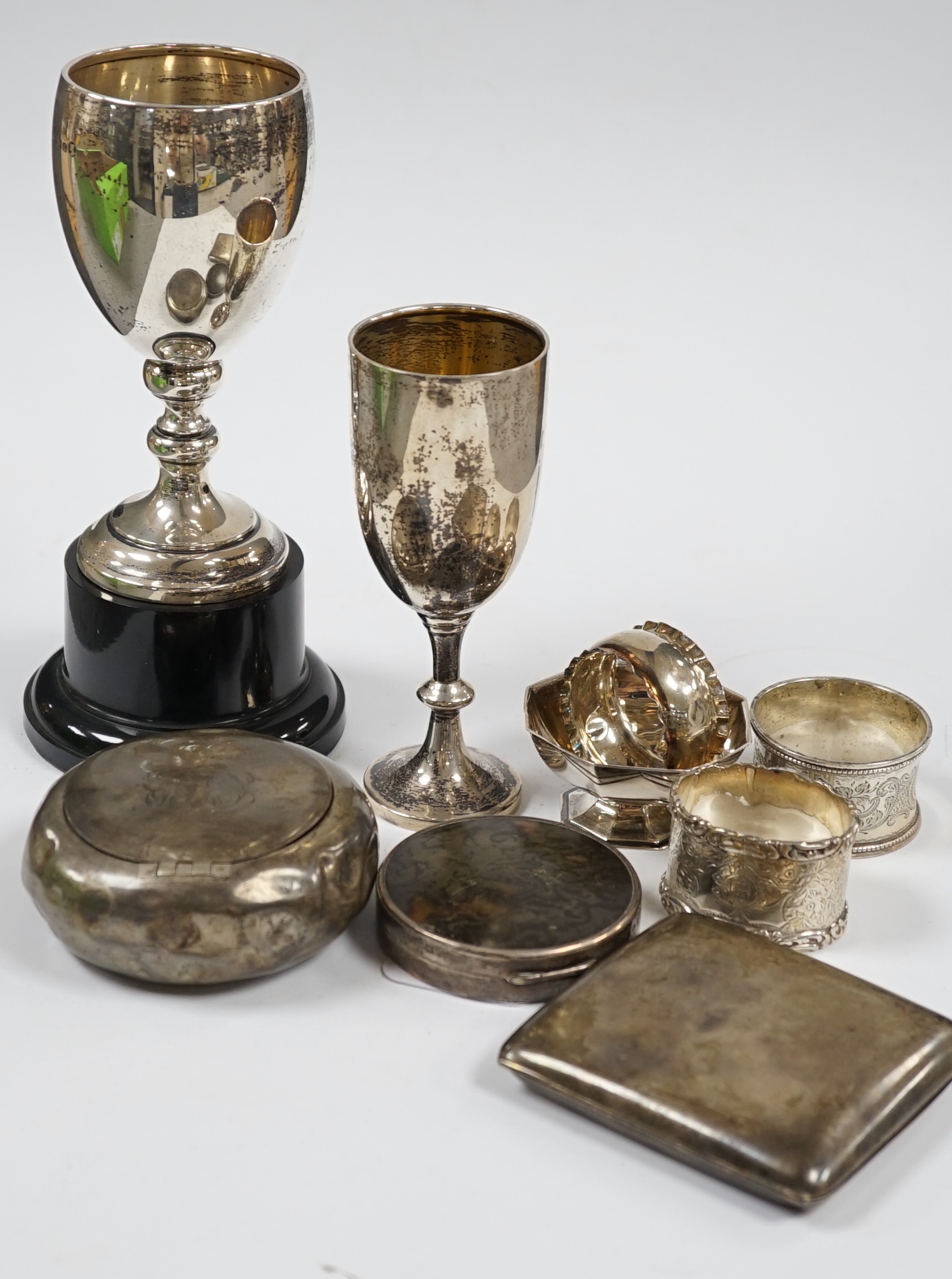 Sundry small silver including a tortoiseshell mounted compact, tobacco box (a.f.), two small trophy cups, napkin rings, condiment etc. and a Sampson Mordan & Co. yellow metal overlaid propelling pencil. Condition - poor